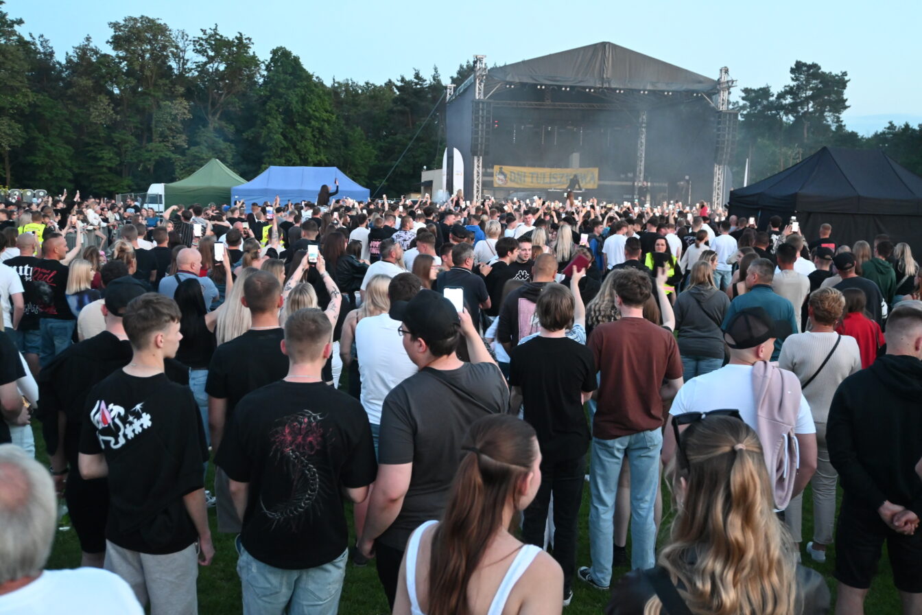 Tłum mieszkańców Tuliszkowa bawiący się pod sceną amfiteatru wieczorem. Ludzie klaszczą, trzymają w górze telefony i świecące gadżety.